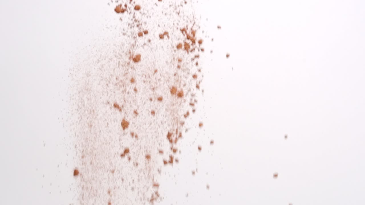 느린 동작으로 흰색 배경에 비가 내리는 베이킹을 위한 초콜릿 갈색 코코아 가루 성분