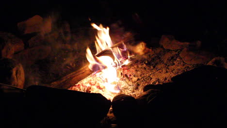 Close-up-of-a-person-poking-a-campfire