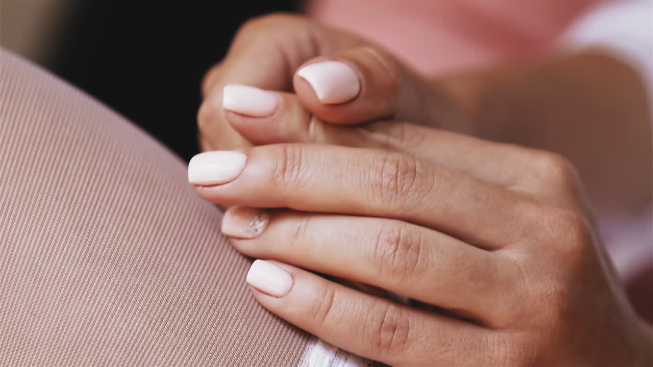 mujer con medias blancas sostiene las manos con una manicura elegante