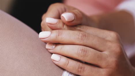 woman in white stockings holds hands with elegant manicure