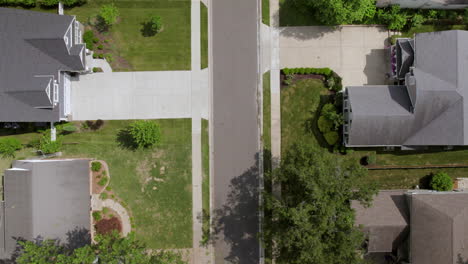 Overhead-push-up-a-suburban-street-in-a-nice-neighborhood-with-a-white-car-driving-down-the-street-and-out-of-frame