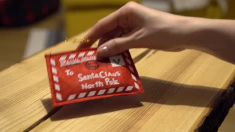 packing money into red christmas decorated envelope on wooden table