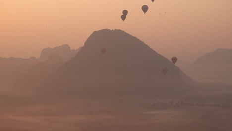 hot air balloons rising over mountain during sunrise in Vang Vieng, the adventure capital of Laos