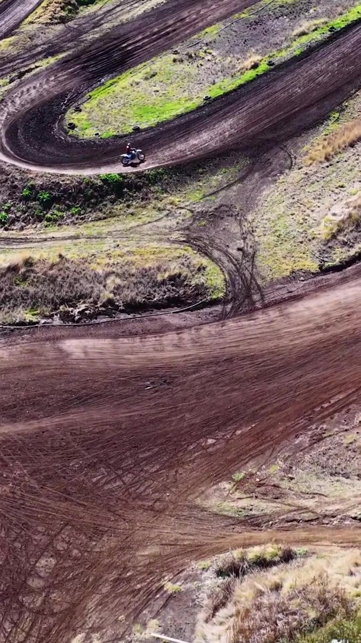 Una ripresa aerea con drone segue una moto da cross che percorre un sentiero tortuoso attraverso la boscaglia australiana