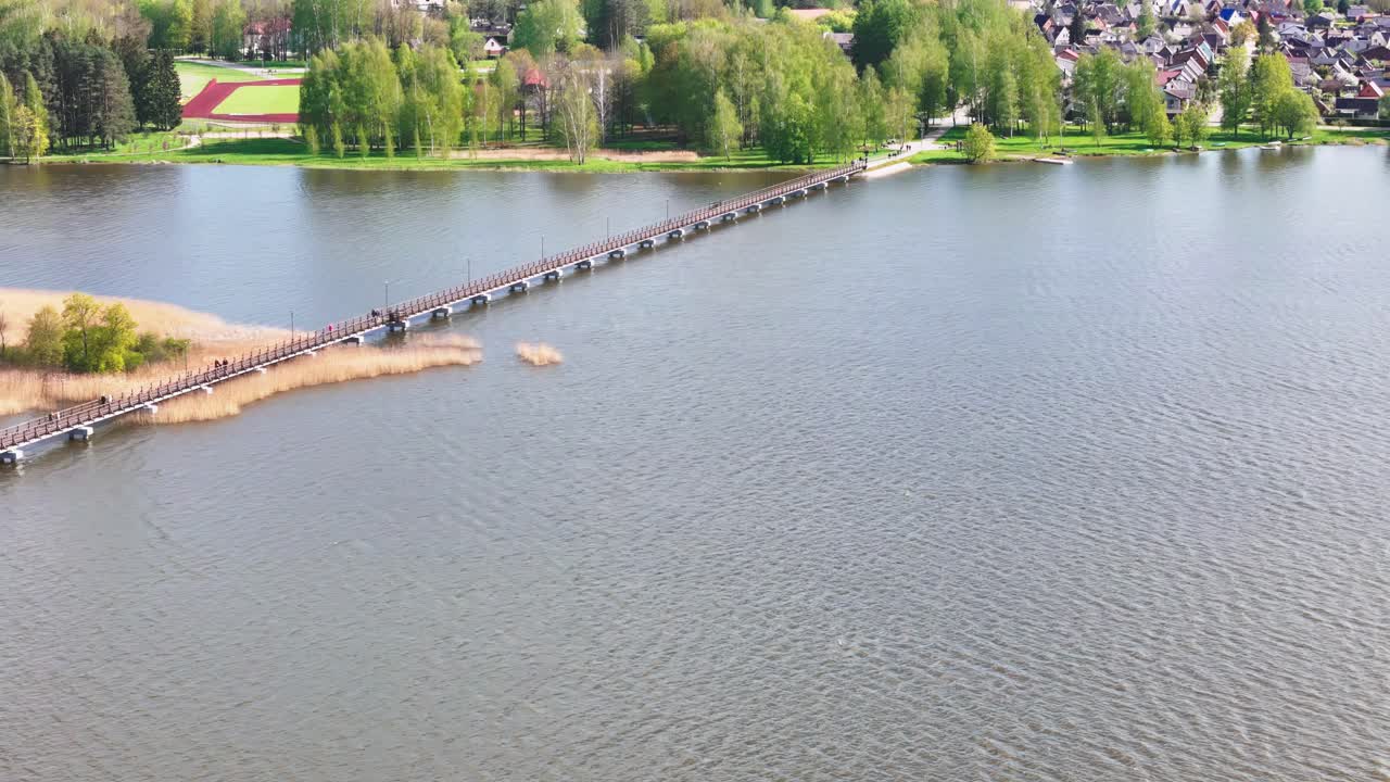 A Scenic View of the Širvėna Lake Footbridge, a Wooden Path Linking Astravas Manor With the Town of Biržai, Lithuania - Aerial Drone Shot
