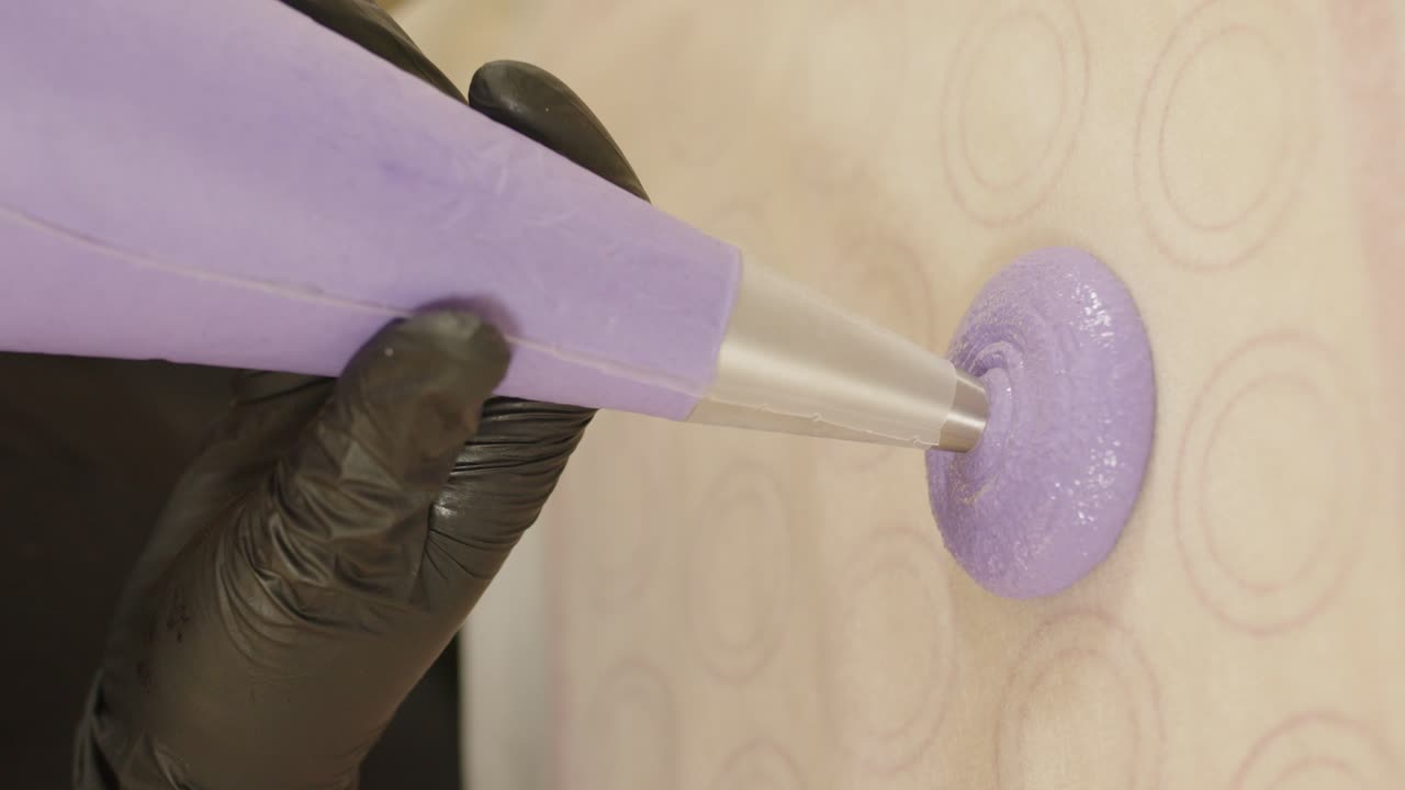 manos sosteniendo bolsa de pastelería, confeccionando coloridos macarons