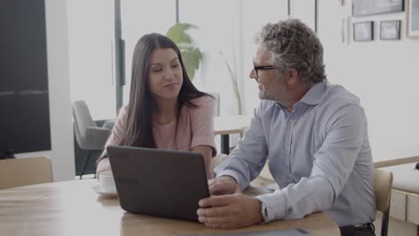 Cheerful-colleagues-chatting-and-using-laptop