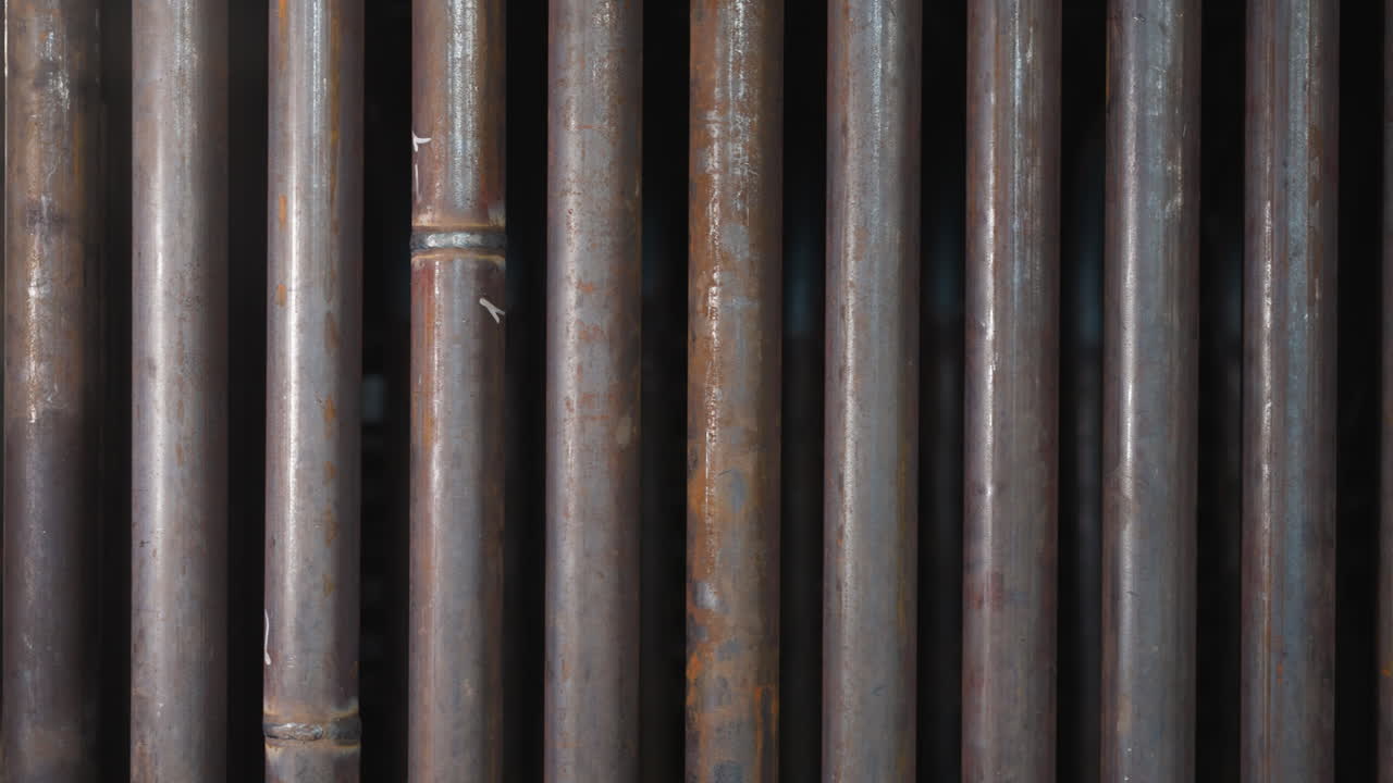 tubos metálicos en fila con costuras de soldadura en el almacén de la fábrica