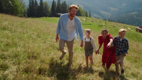 Friendly-family-walking-mountain-slope-sunny-day.-Parents-holding-children-hands