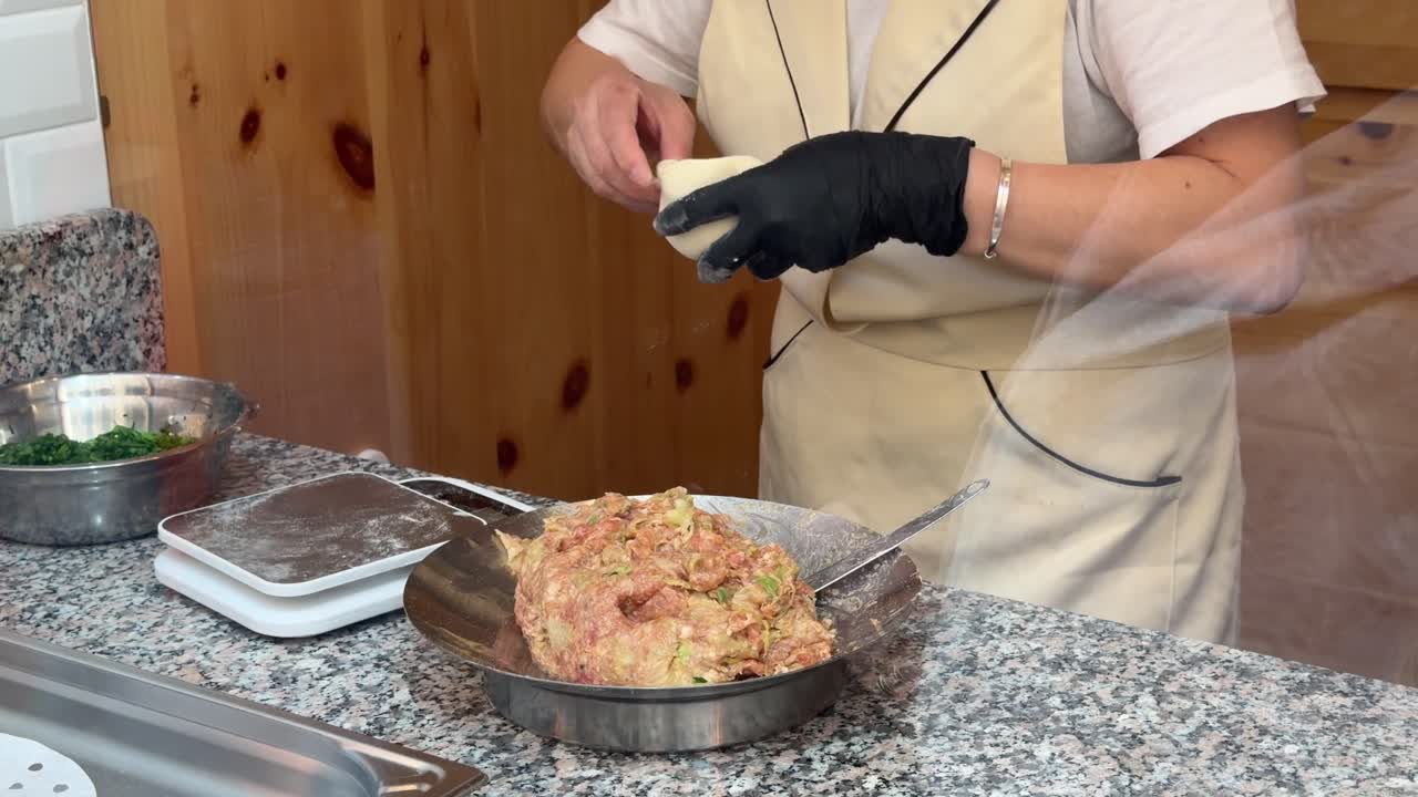Chef che prepara ravioli a mano in una cucina professionale.