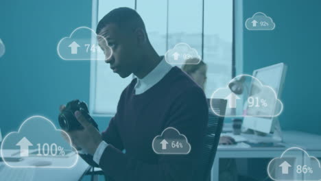 animation of clouds with growing numbers over african american businessman working in office