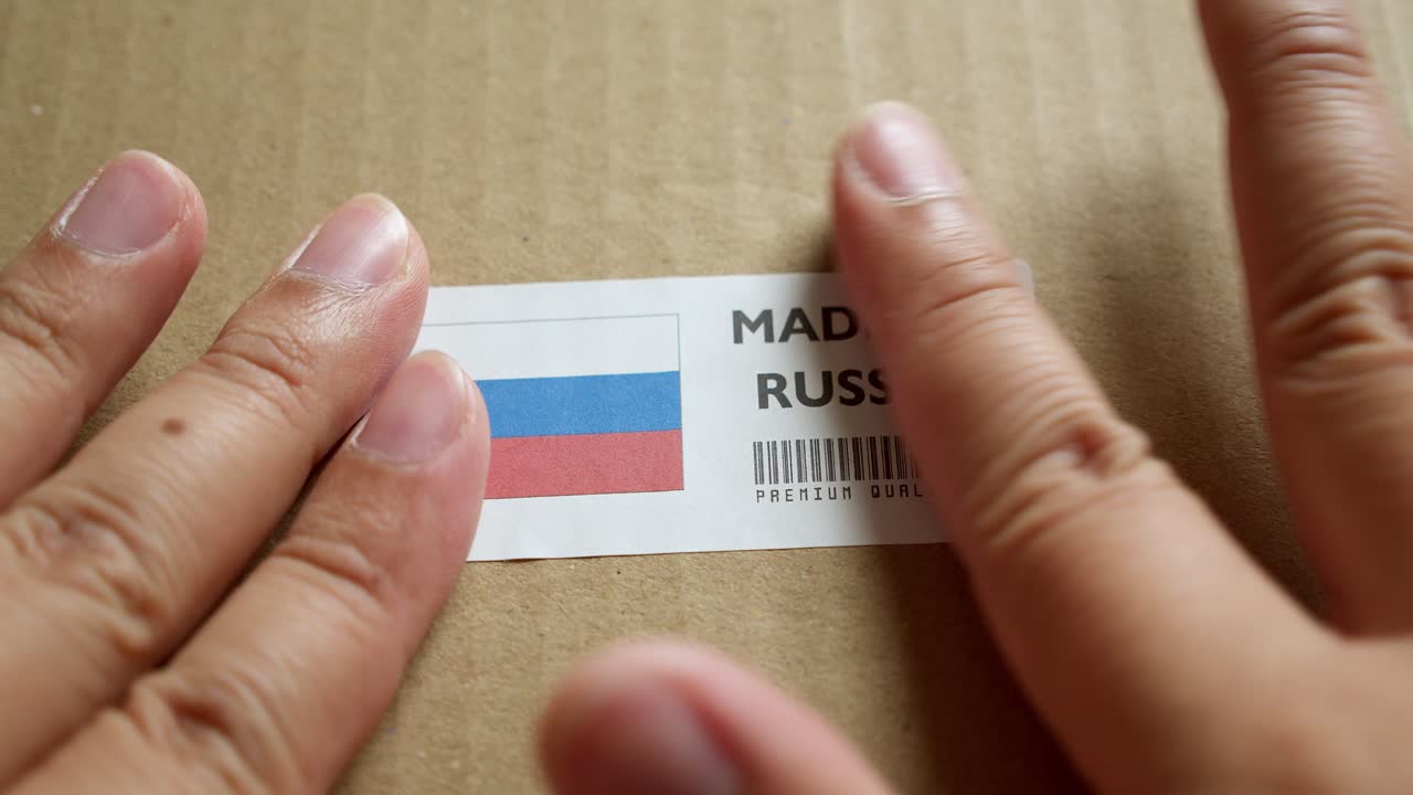 Sticking a sticker with the Russian flag and a bar code on a box for export that is being prepared for shipment