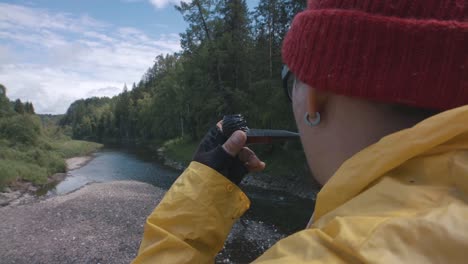 hombre fumando pipa junto a un río en el bosque