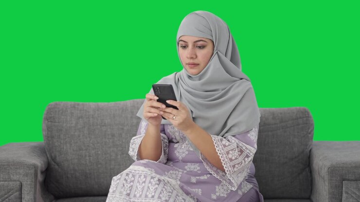 Muslim woman messaging someone on phone Green screen