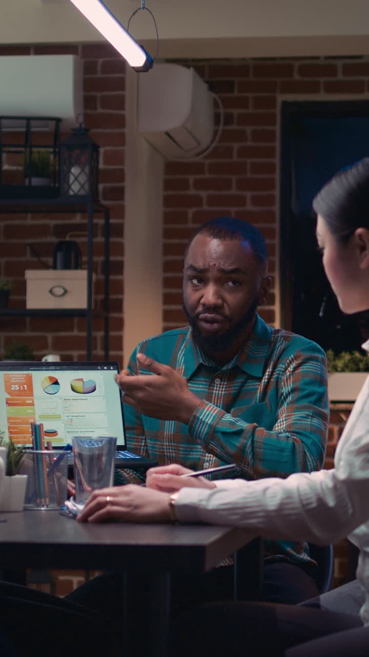 Vertical video: Coworkers brainstorming, analyst showing revenue statistics on laptop screen