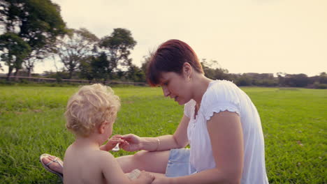 Mother-feeding-child-yogurt-outdoors