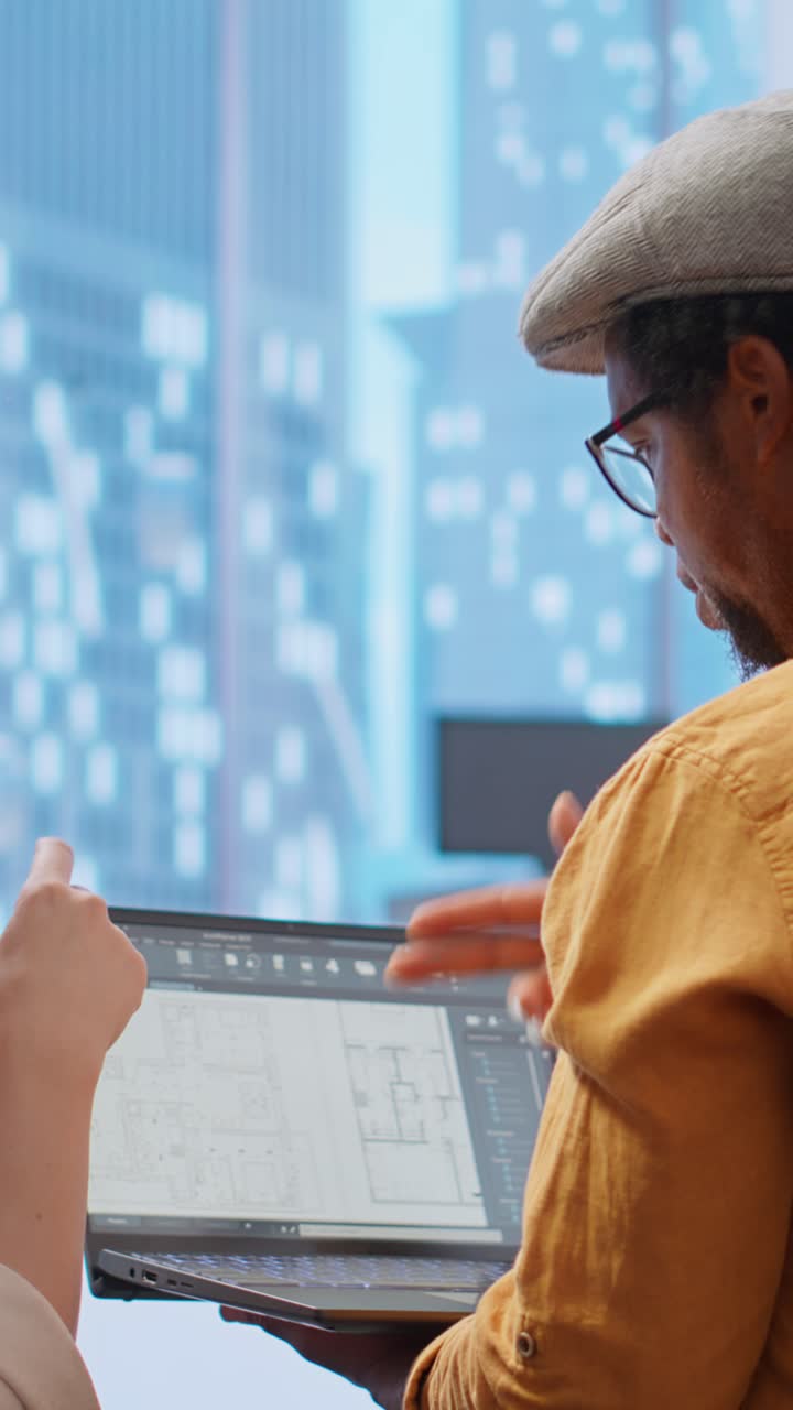 Business Colleagues Discussing Architectural Plans on Laptop in Office