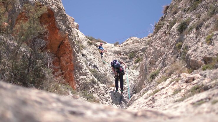 Via ferrata ascension by a couple sportsmen. View of mountain and mountaineers climbing in Alicante, Spain.