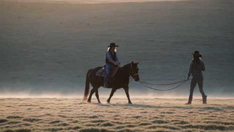 women horseback riding in sunrise meadow