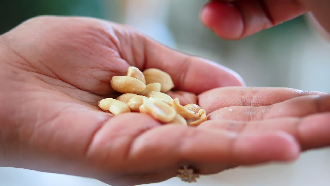 Close-up of Hand Picking Roasted Peanuts from Palm