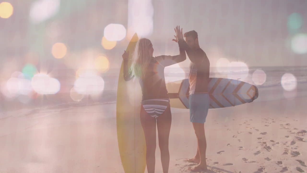 On beach, surfers giving high five with animation of bokeh light effects