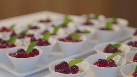 cerca de muchas tazas de compole de cerezas con hojas de menta presentadas en tazas de porcelana blanca en un buffet