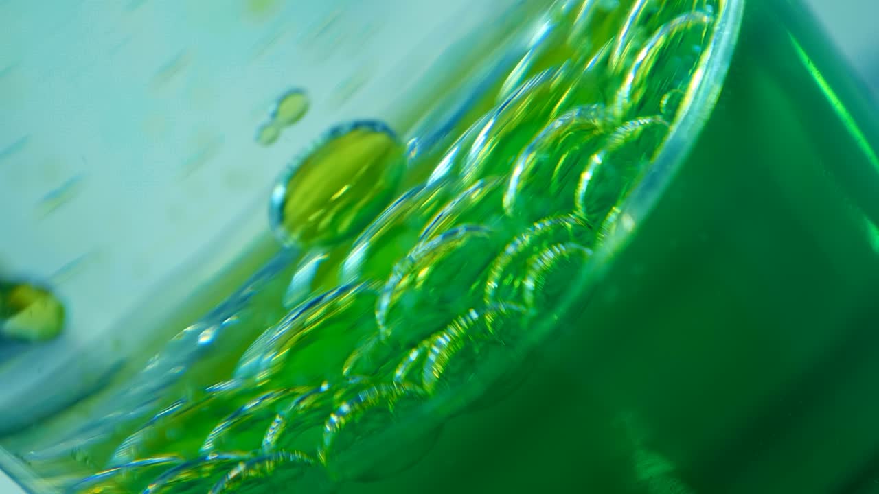 녹색 기름의 물방울은 천천히 물의 바닥으로 떨어집니다.