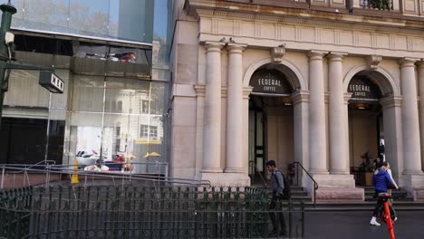 pedestrians walking past historic building in melbourne