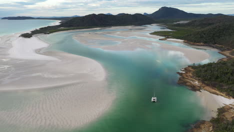 wide rising drone shot of whitehaven beach whitsunday island australia with sailboat in water