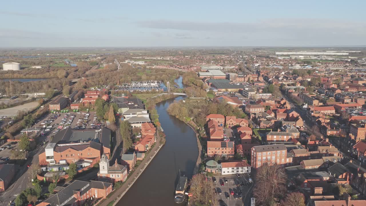 Newark on Trent displaying its townscape from an aerial perspective, highlighting the meandering River Trent, historic architecture, and the surrounding green areas on a clear day