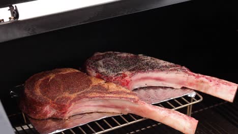 pan de dos bistecs tomahawk sazonados y frotados con especias crudas en una rejilla para fumadores en la parrilla