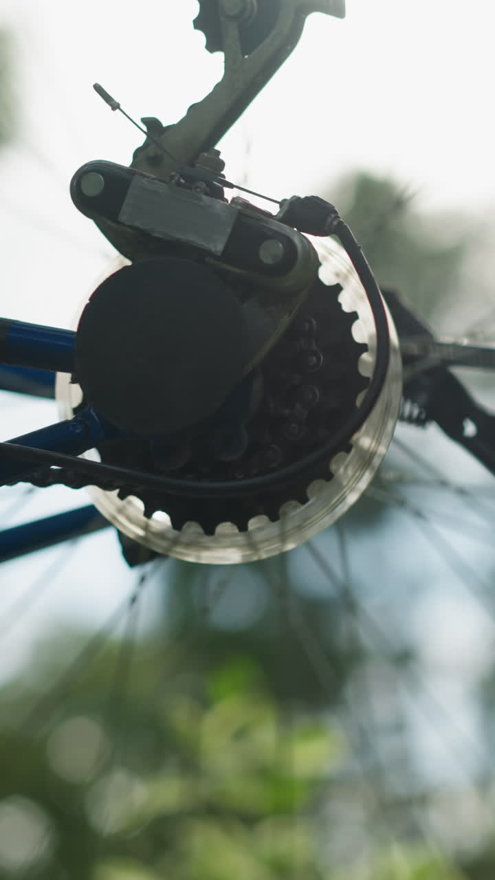 자전거의 뒷바와 기어 시스템의 클로즈업, 바가 잠시 회전할 때, 체인과 바가 초점을 맞추고, 배경의 초록색은 흐릿합니다.
