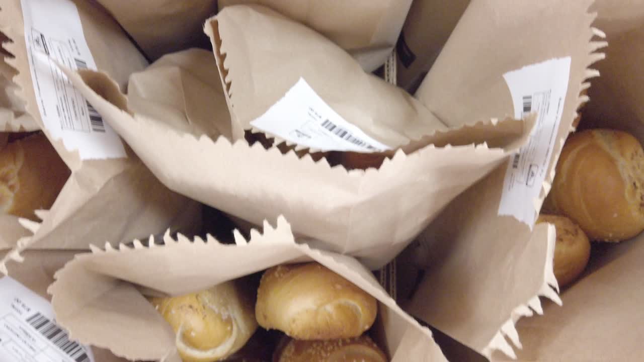 Zenithal view of fresh bread loaves packed inside paper bags at bakery