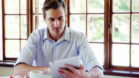 Man-using-digital-tablet-while-having-coffee