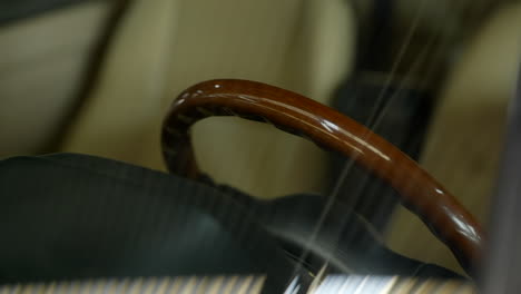 Stylish-vintage-wooden-steering-wheel-behind-car-windshield-reflecting-under-warehouse-lighting