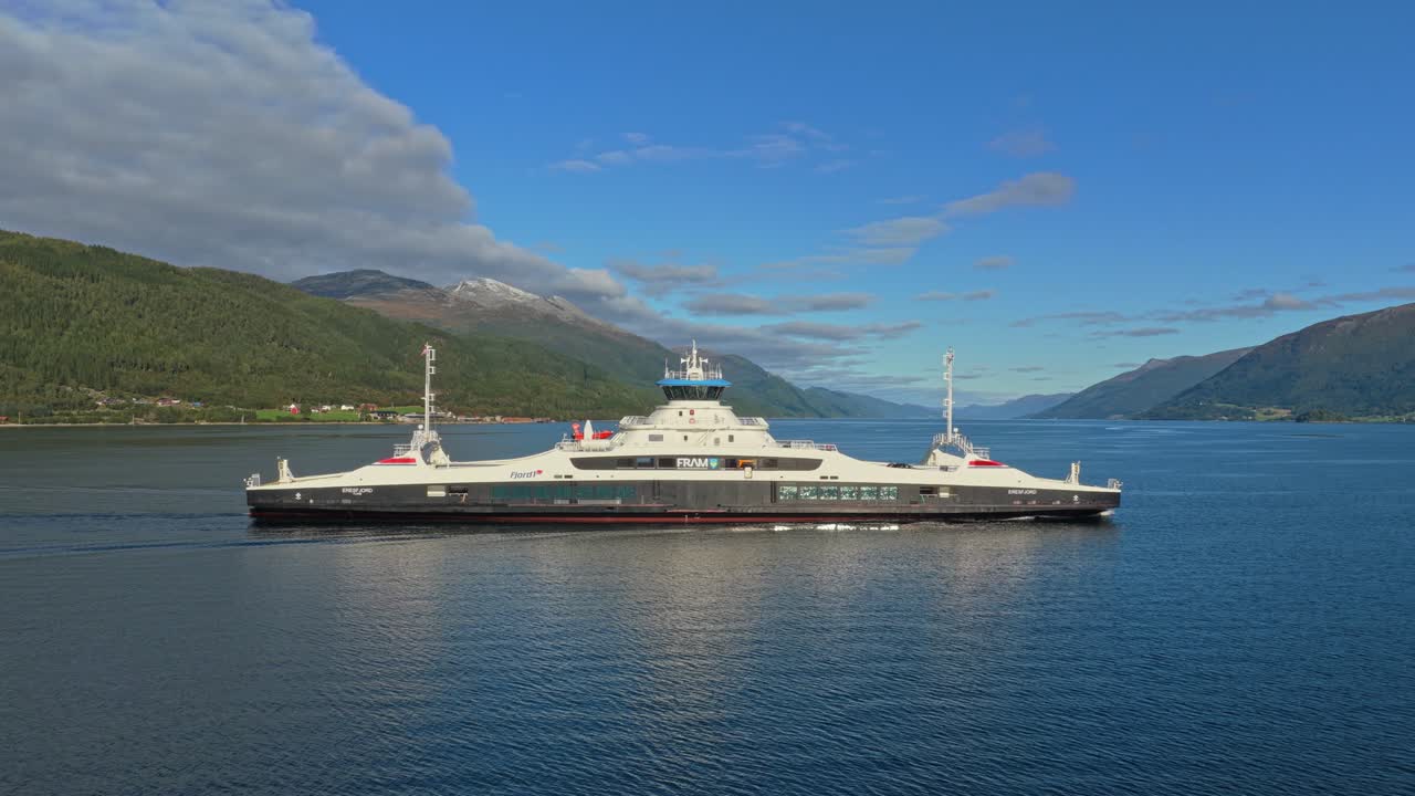 Miljøvenlig færge sejler hurtigt hen over en fredelig norsk fjord, droneoptagelse.