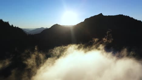 morning sun above mountain peaks and clouds above valley, cinematic aerial view