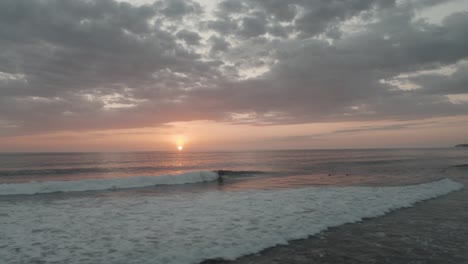 aéreo, tiro de drones panorámico con las olas en la playa de costa rica durante la puesta de sol