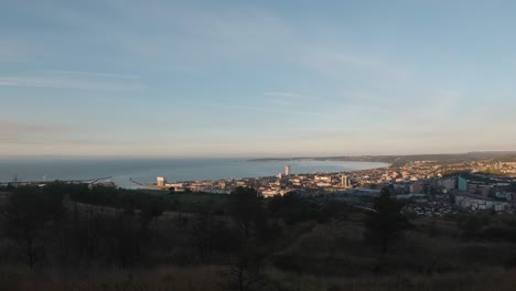 pan across moorland with swansea cityscape in distance at sunrise