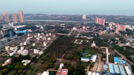 aerial view of a urban landscape chennai, india. a diverse mix of developed and developing areas, modern high-rise buildings in the distance contrasting with residential structures and open plots.