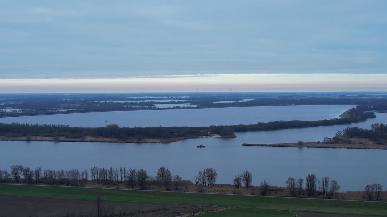 흐린 날 네덜란드 남부의 강 하류를 여행하는 작은 순양함의 와이드 샷