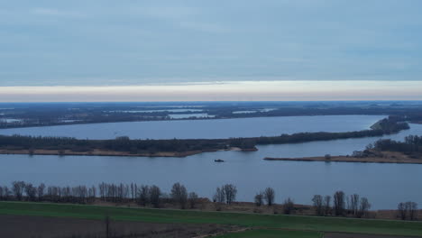 Wide-shot-of-a-small-cruiser-traveling-downstream-the-river-in-south-Netherland-on-a-cloudy-day