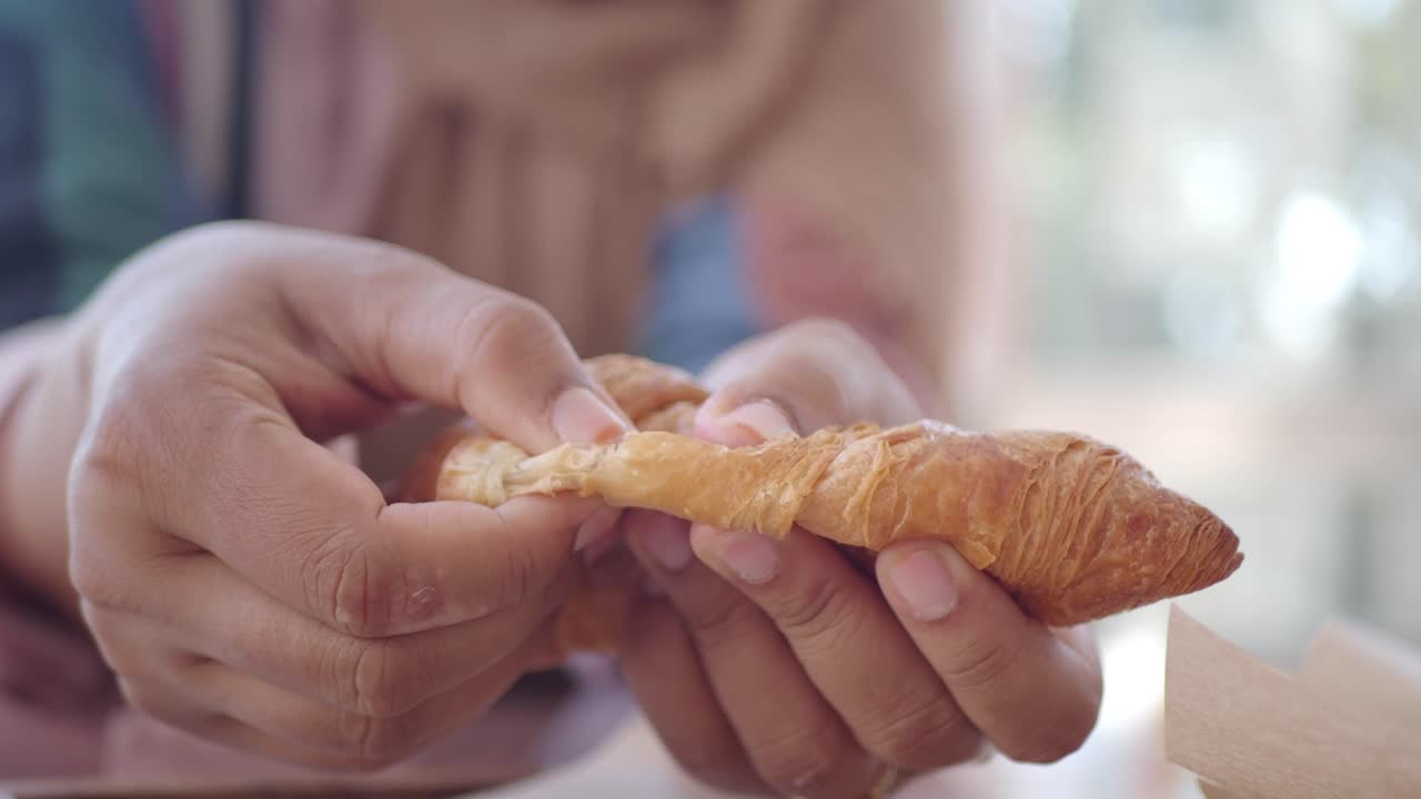 Close-up of person eating a croissant