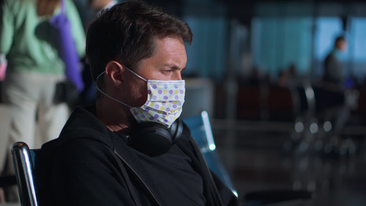 hombre con una máscara de cara esperando en el aeropuerto