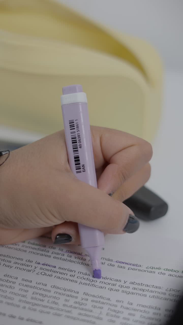 A person's hand highlighting text on a document with a purple marker