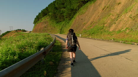 young-woman-begins-her-journey-as-she-steadily-walks-up-a-hill-while-wearing-a-backpack-for-adventure