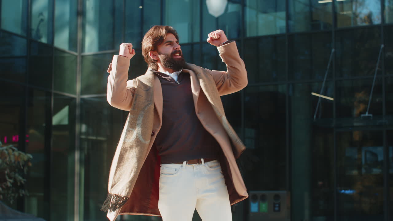 hombre emocionado mirando sorprendido cerrando los puños conmocionado por la victoria repentina de pie en la calle de la ciudad
