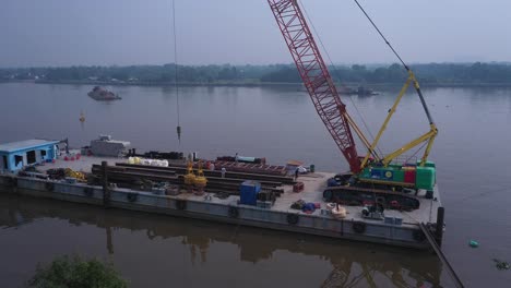 aerial fly in to dredging equipment and workers on a barge on the saigon river in ho chi minh city, vietnam