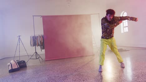 happy biracial male dancer dancing alone in dance studio, slow motion