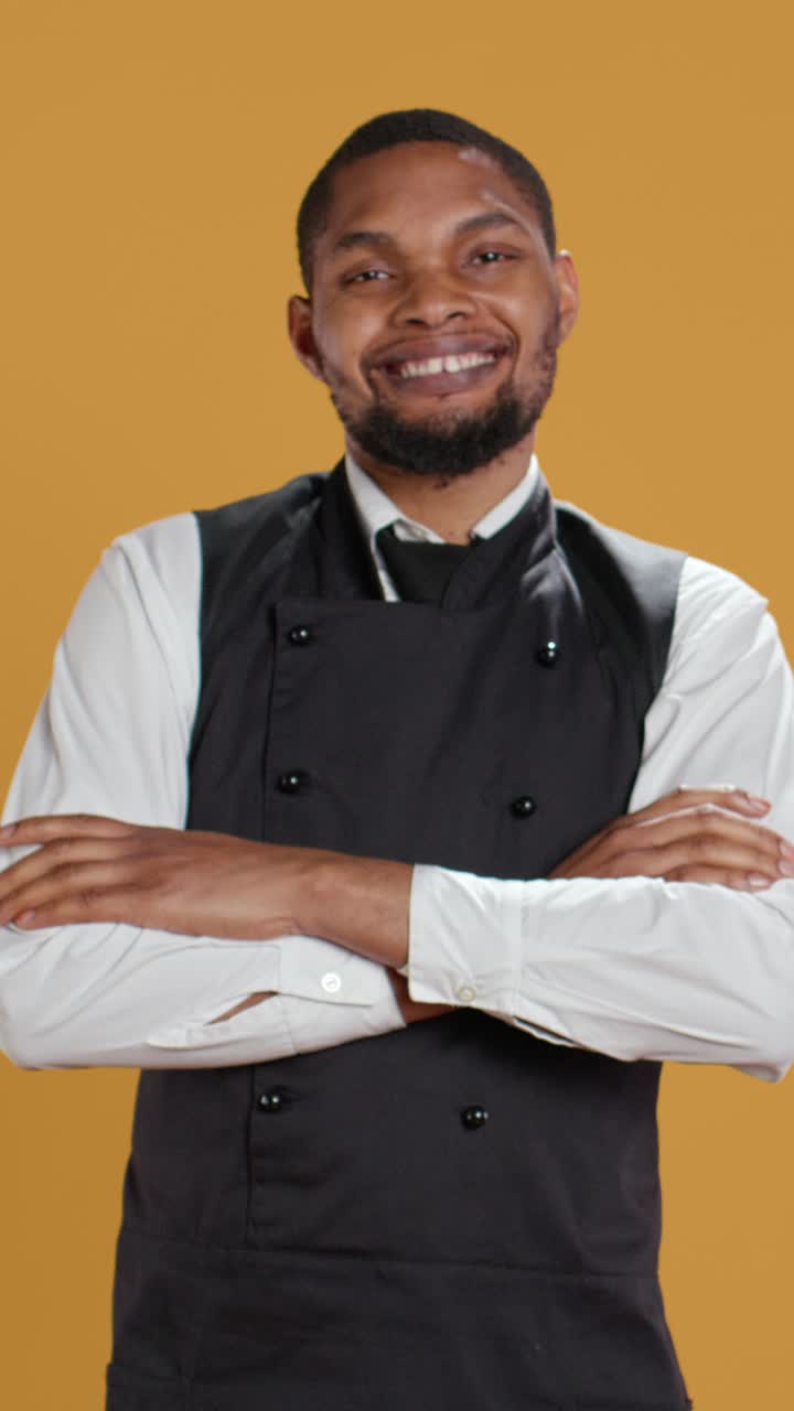 Chef afroamericano sorridente e sicuro di sé che incrocia le braccia